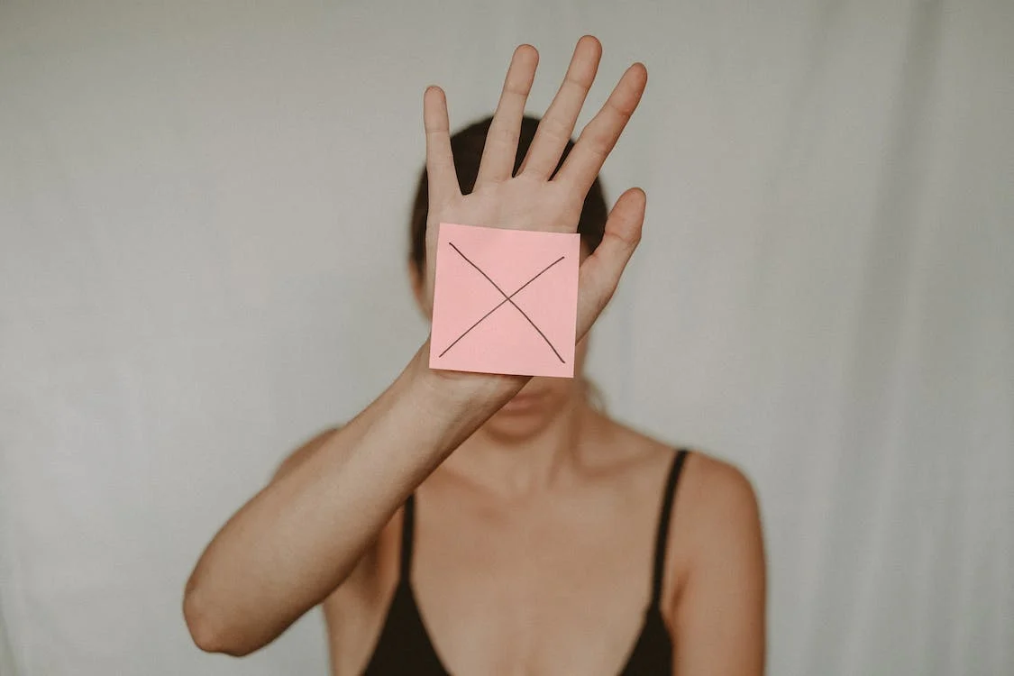 Seorang perempuan menempelkan gambar x ditangan | picture by Anete Lusina on unsplash.com